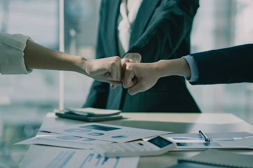 Três pessoas se cumprimentando em um ambiente corporativo