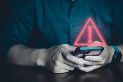 Pessoa utilizando o celular com um sinal de aviso digital