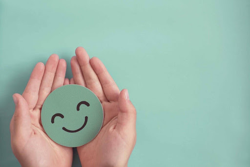 Mãos segurando emoji feliz