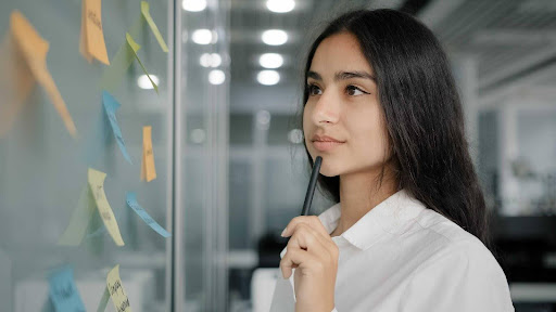 Mulher em seu ambiente de trabalho com uma caneta na mão
