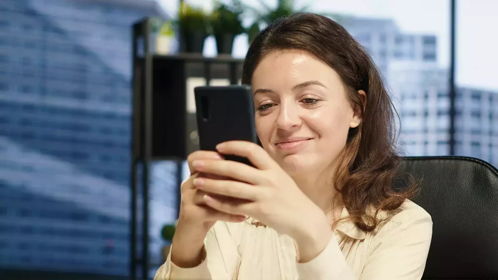 Colaboradora acessa a rede social corporativa pelo celular